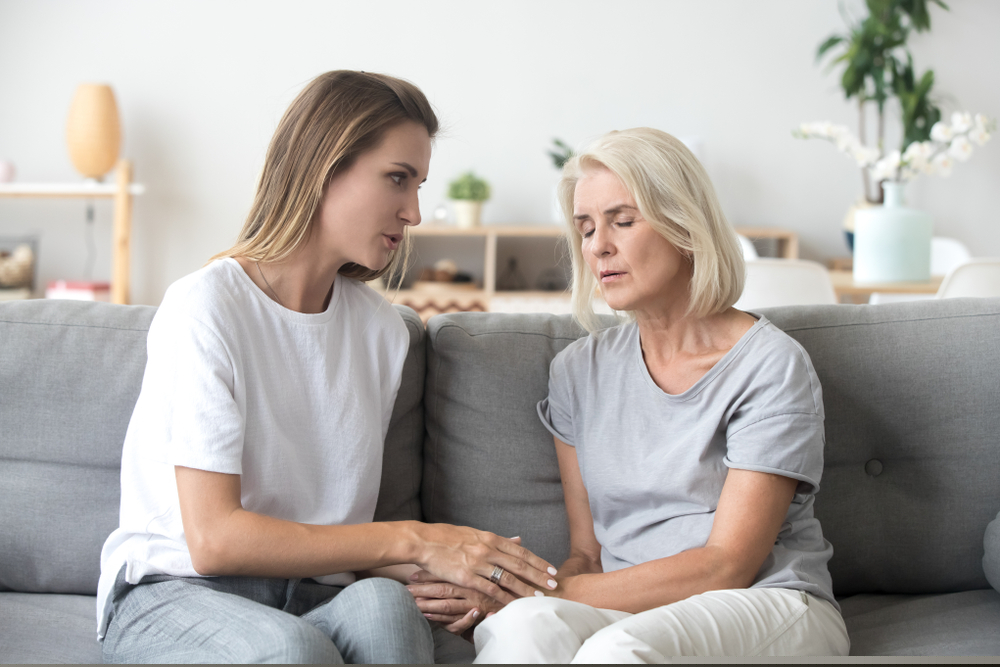 Adult Daughter Holding Hands With Grieving Mother